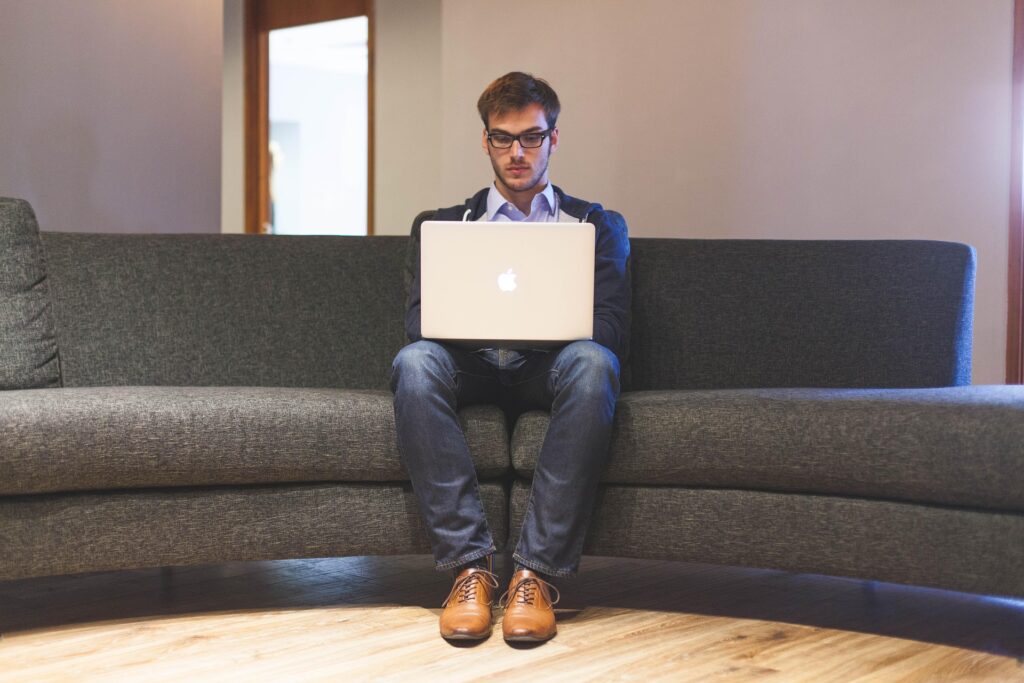 Mann mit Laptop auf Sofa